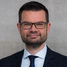 Bundesjustizminister Marco Buschmann im Porträt vor grauem Hintergrund